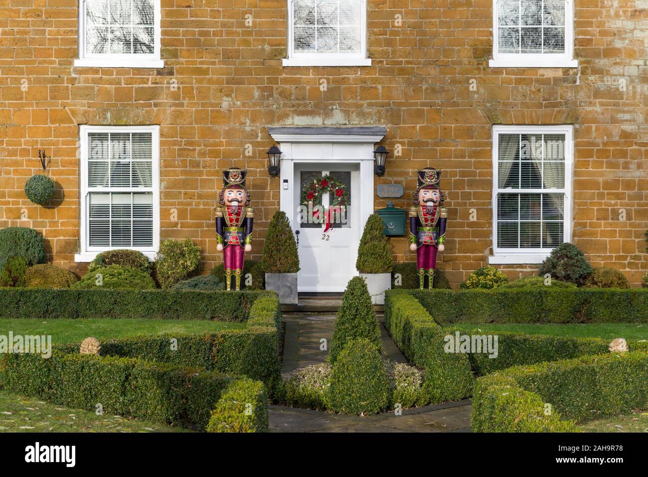 Frente a una propiedad de época en Navidad con dos figuras de Nutcracker de tamaño natural junto a la puerta principal; Milton Malsor, Northamptonshire, Reino Unido Foto de stock