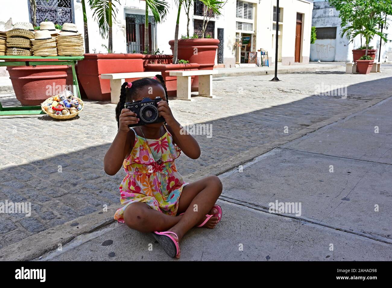 25.07.2019, Cienfuegos, Cienfuegos, Cuba - cuba pequeña niña sentada en la  calle y toma fotos con una analógica, antigua cámara reflex Zenit espejo.  Tod Fotografía de stock - Alamy