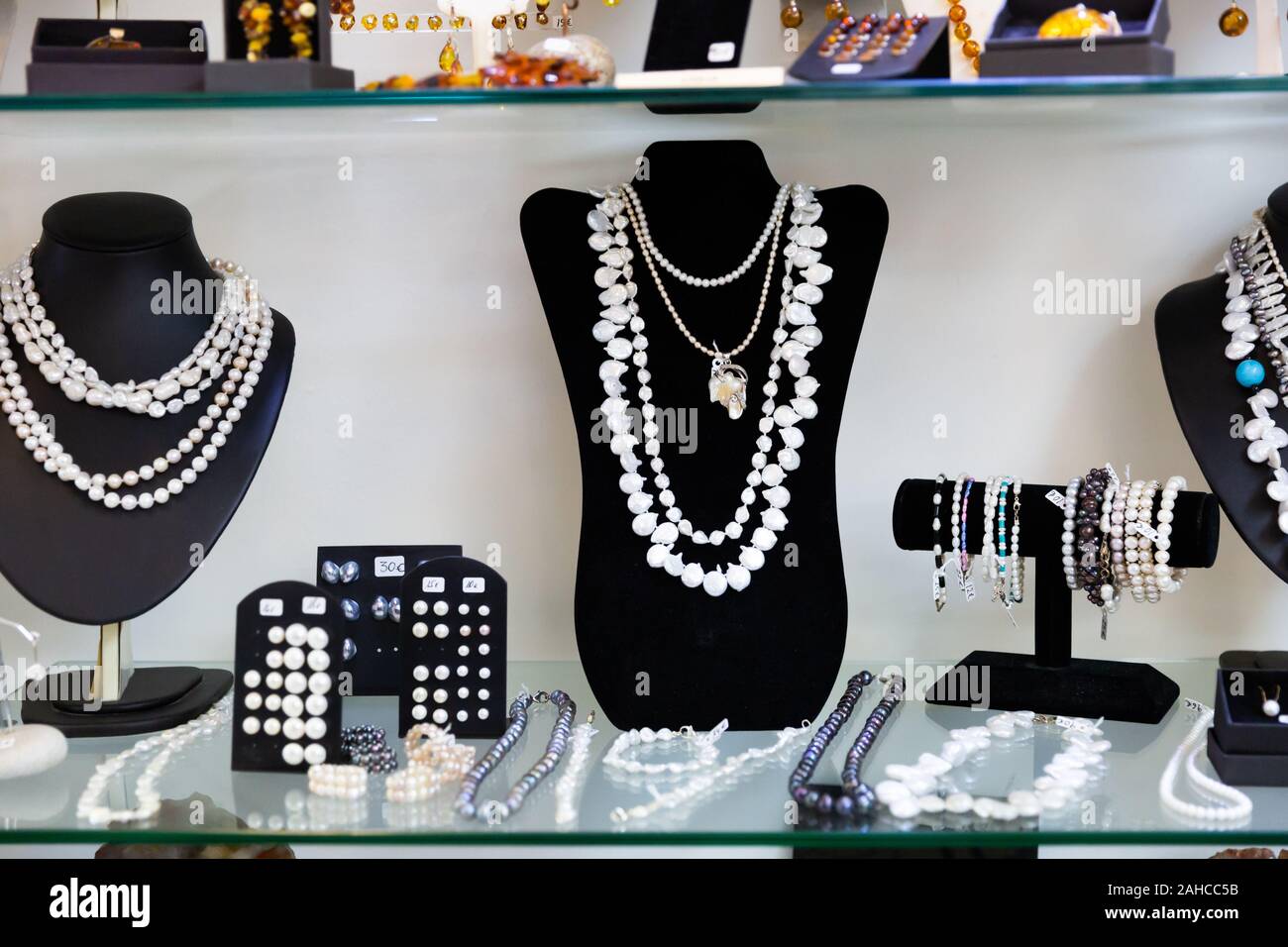 Variedad de collares, pulseras y pendientes de perlas blancas y negras en  los maniquíes en joyería cristal Fotografía de stock - Alamy
