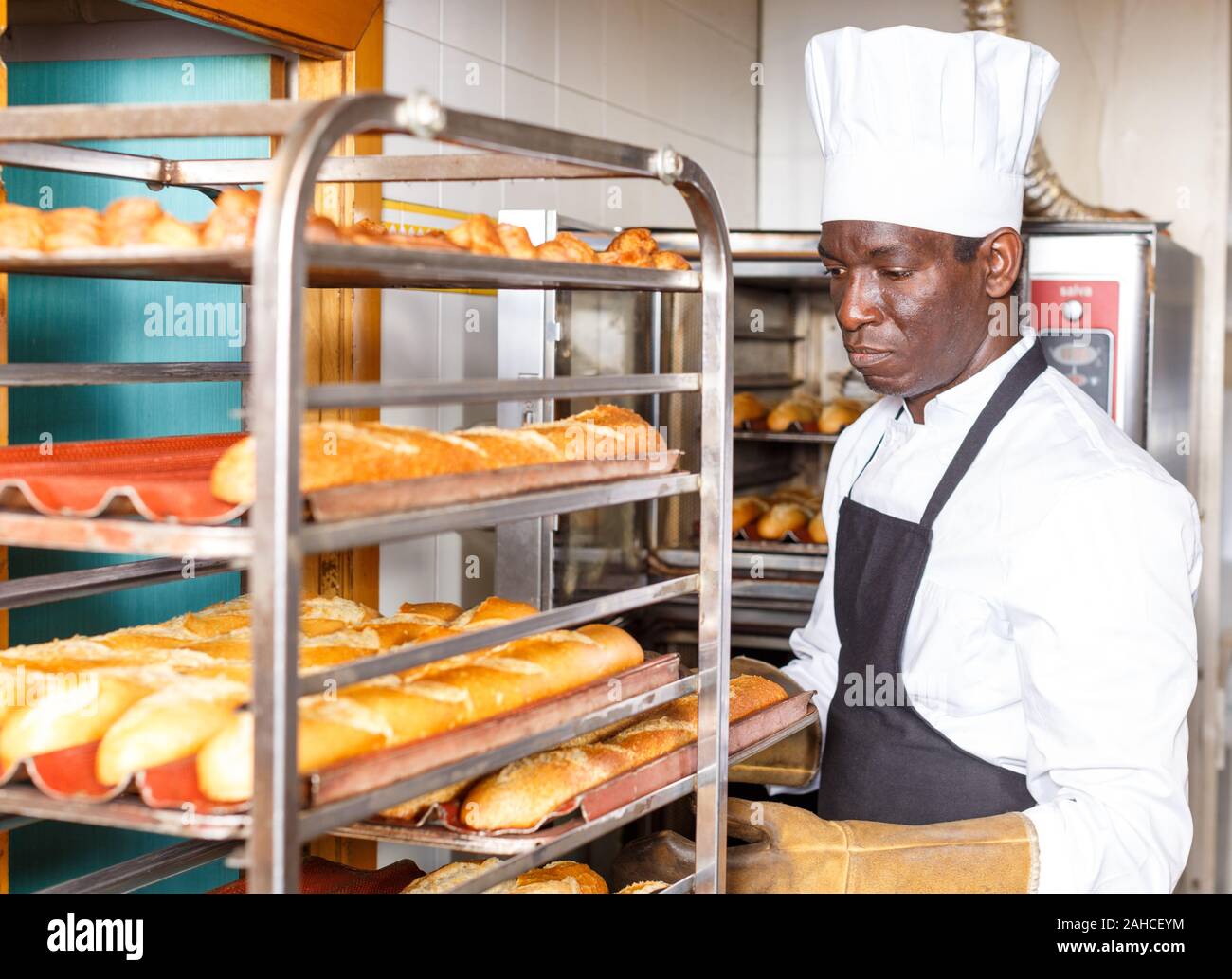 Baker experimentados que trabajan en la pequeña panadería, sacar el pan del  horno industrial y poner en rack Fotografía de stock - Alamy