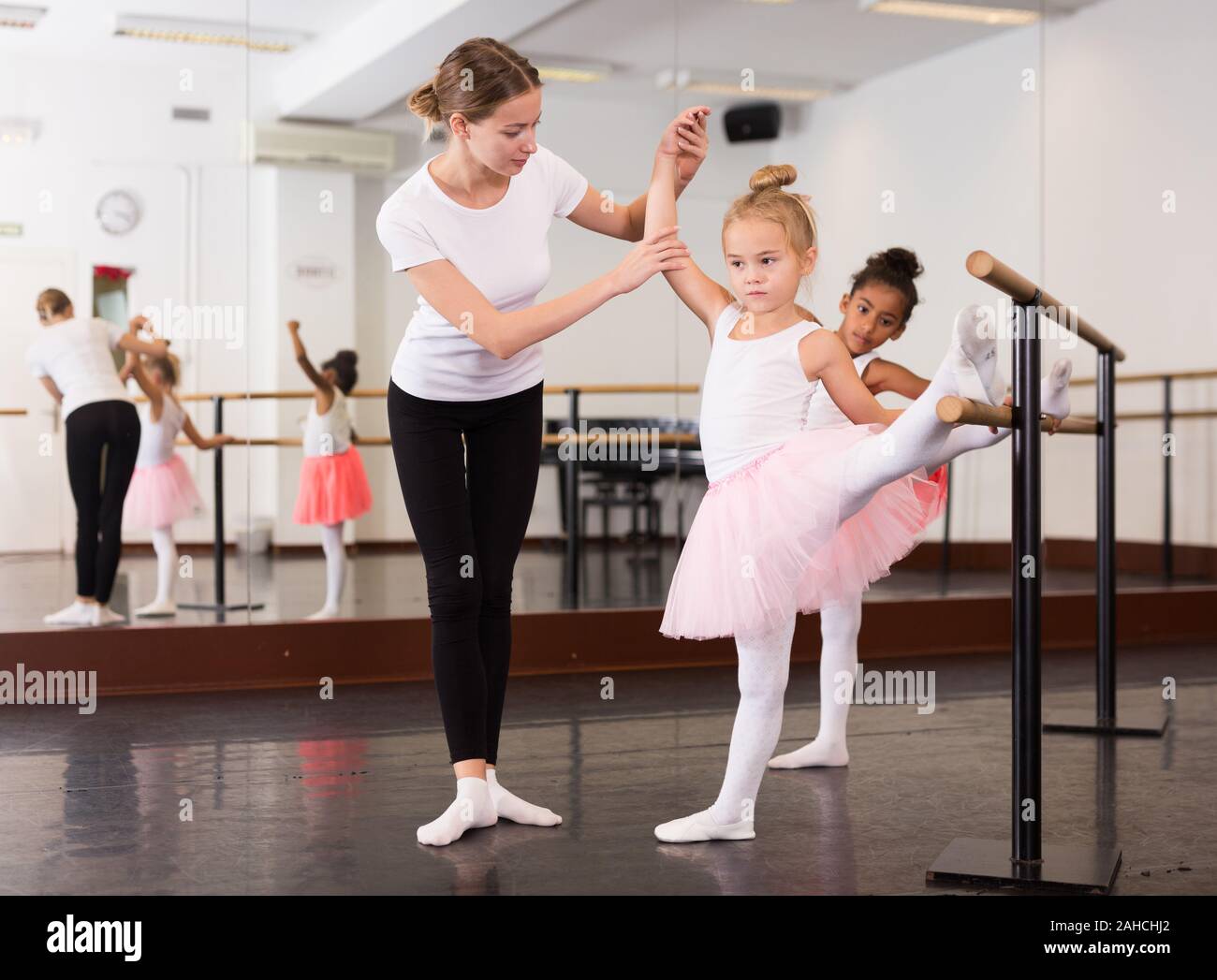 Ballet femenino trainer enseñar dos niñas cerca de ballet barre en salón de  baile Fotografía de stock - Alamy