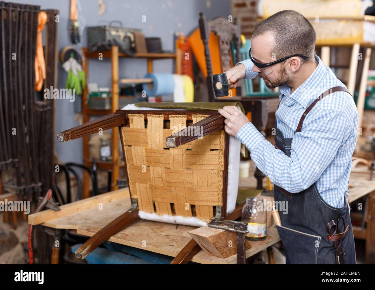 Obrero calificado en silla de tapicería de muebles taller de reparación Foto de stock