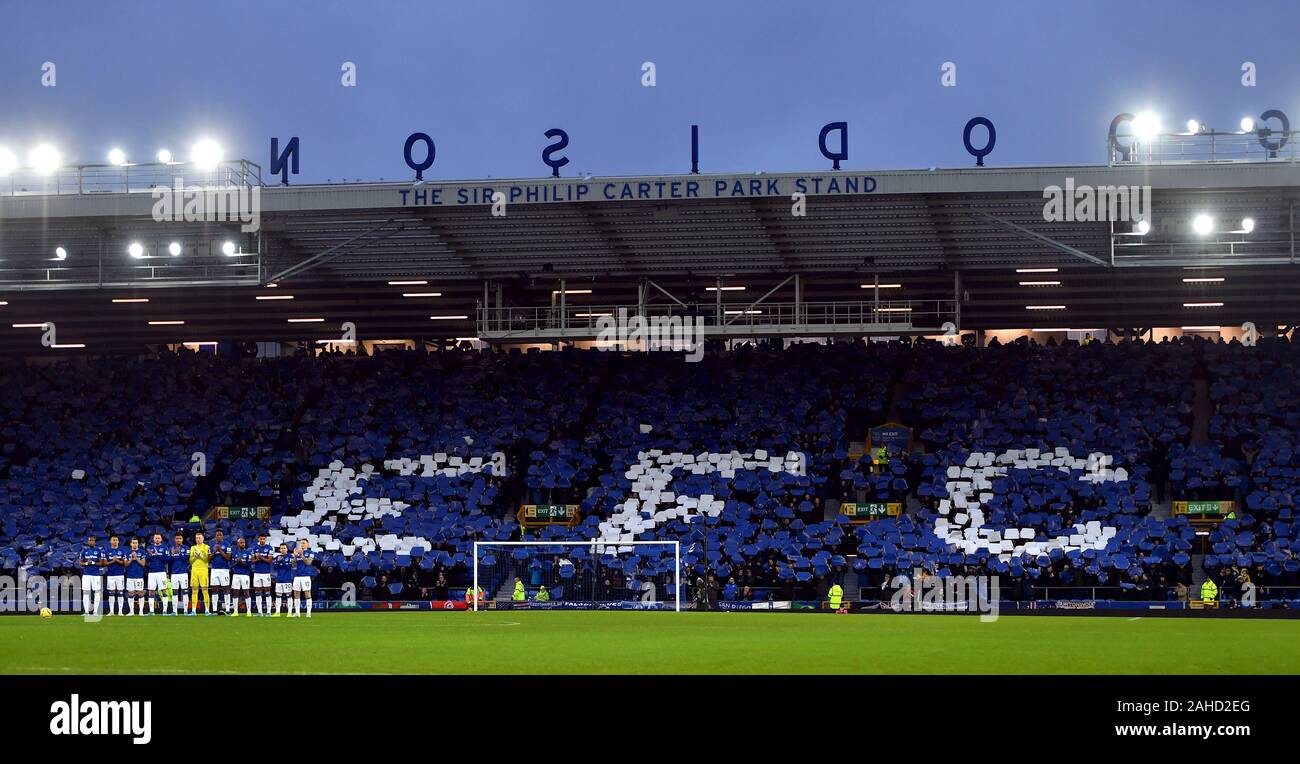 Fans del Everton forman una pared de color azul y un mural en el EFC se erige como los jugadores participan en un minuto de aplausos antes del partido Foto de stock