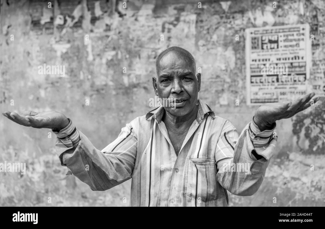 Retrato del hombre que vive en la calle hace gesto interrogatorio contra la pared pintarrajeada en Udaipur, Rajasthan, India. Foto de stock