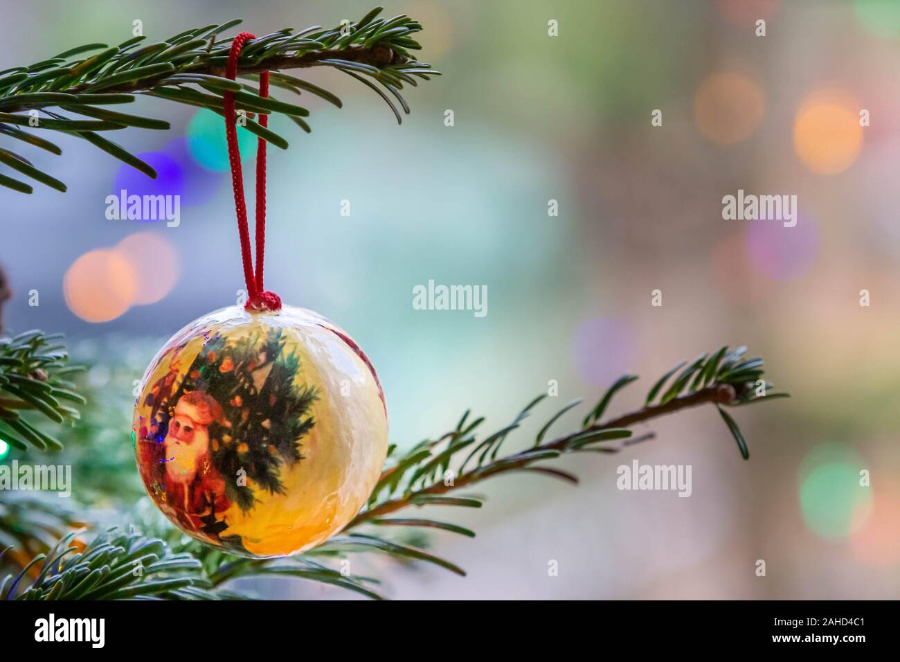 Solo adornos hechos a mano colgando de la rama de un árbol de Navidad con luces de hadas fuera de foco en el fondo Foto de stock
