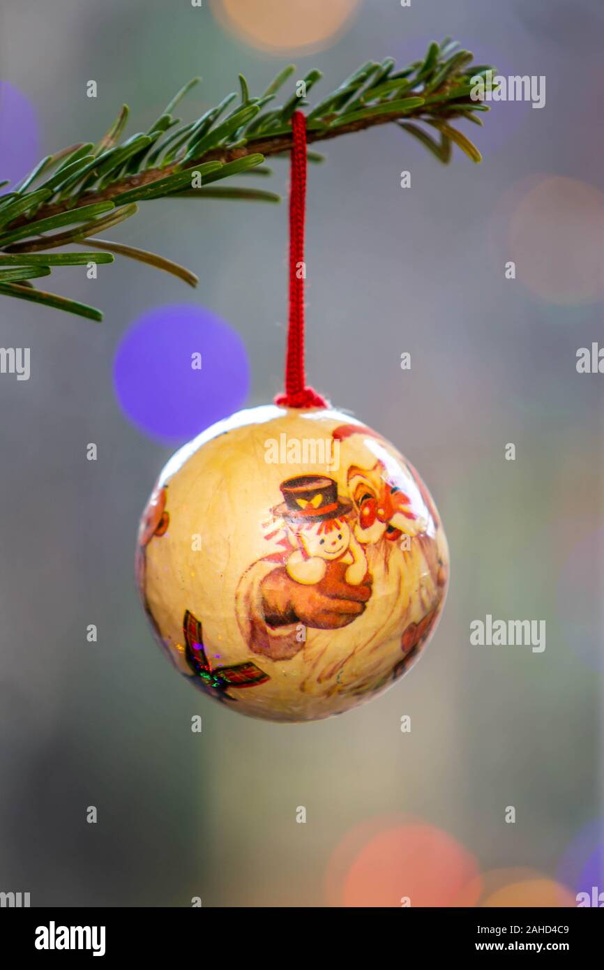 Solo adornos hechos a mano colgando de la rama de un árbol de Navidad con luces de hadas fuera de foco en el fondo Foto de stock