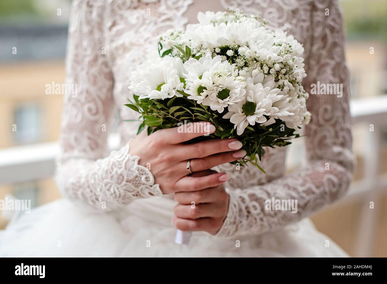 Novia Vestido encaje blanco es la celebración de flores de la boda. Cerca  en las manos de la novia vestidos de anillo de compromiso y la celebración  bouquet de flores blancas Fotografía