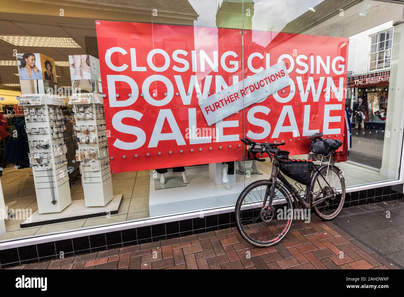 Bicicleta apoyada contra mostrar ventana cerrar la venta, Abergavenny, Wales, REINO UNIDO Foto de stock