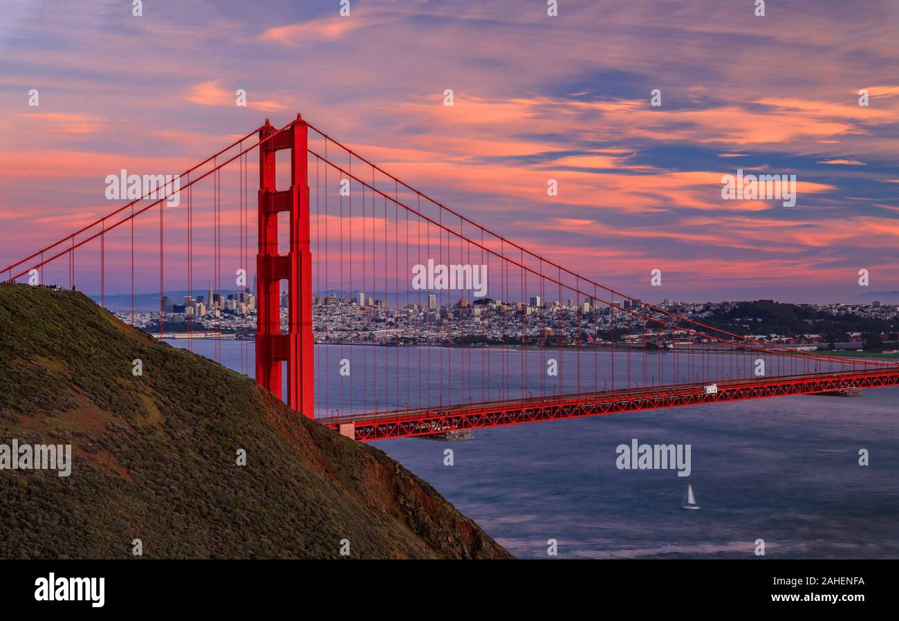 Panorama del puente Golden Gate al atardecer con el Marin en primer plano, el horizonte de San Francisco y las nubes de colores en el fondo Foto de stock