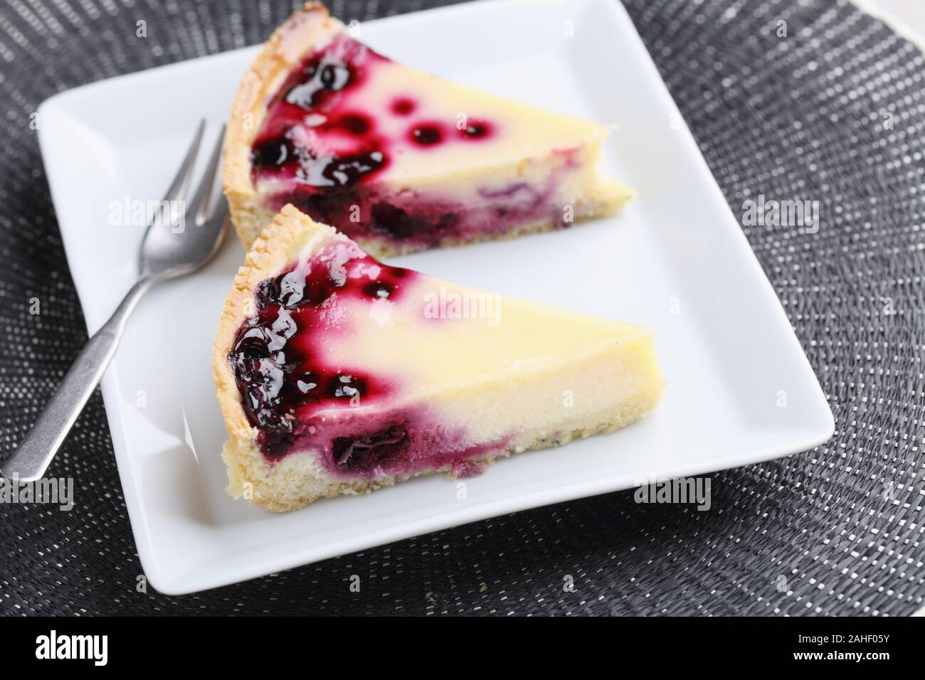 Dos rebanadas de grosella negra cheesecake sobre una placa rectangular blanco Foto de stock