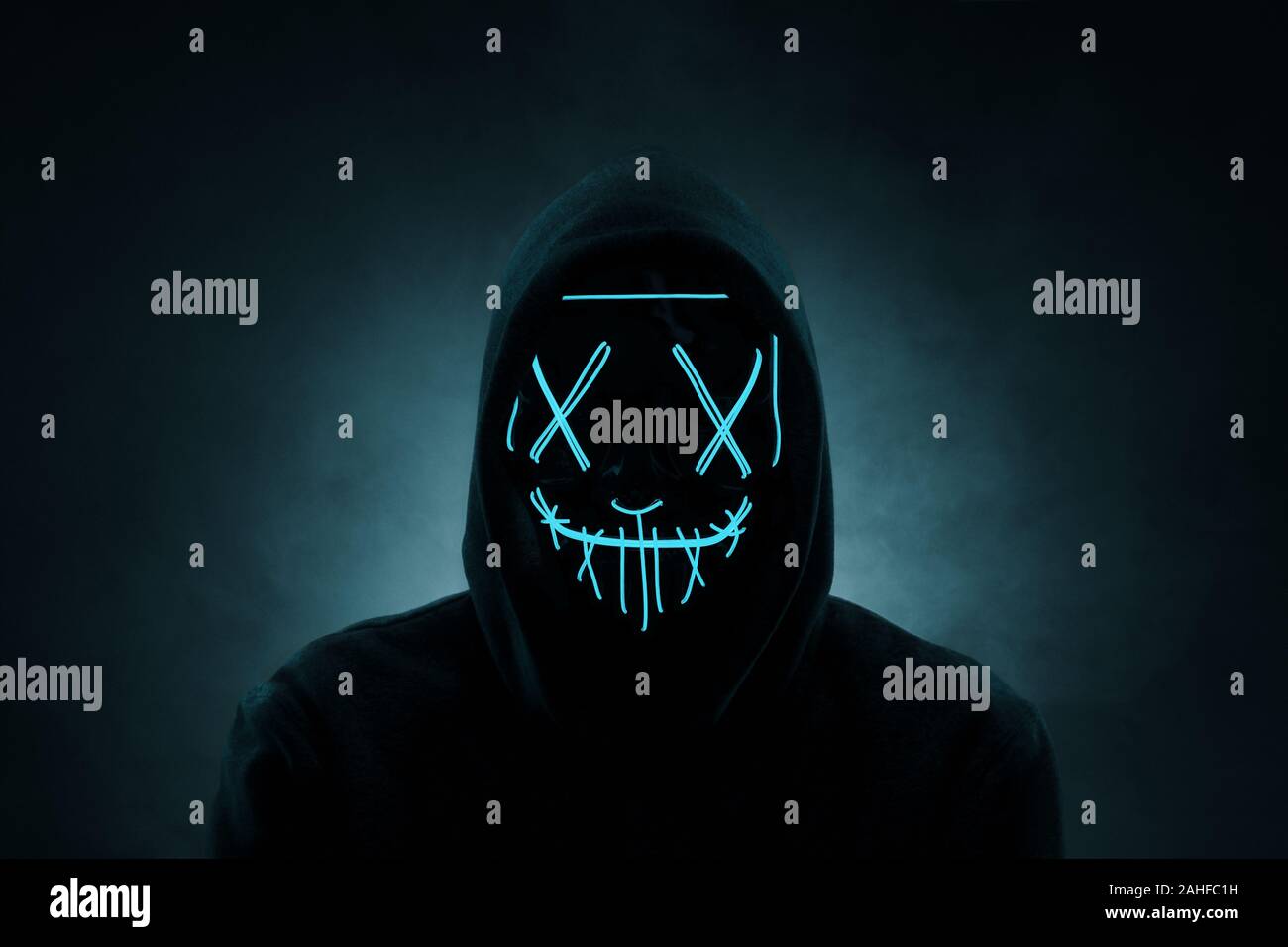 Retrato de un hombre anónimo, hacker vistiendo neon máscara sobre fondo oscuro Foto de stock