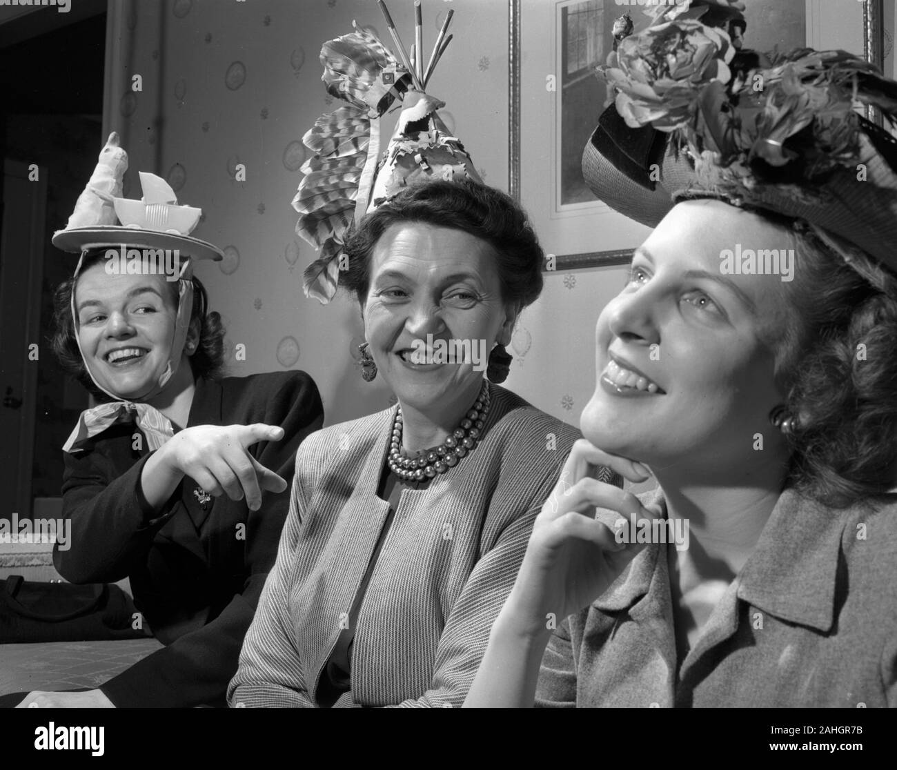Tres mujeres que llevaban varios sombreros divertidos, 1946 Foto de stock