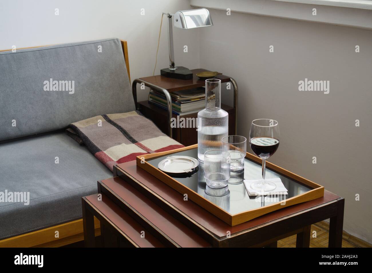 Interior con bodegón - vaso de vino tinto, dos vasos para beber y Garrafa,  cenicero en la bandeja en la mesa, esquina salón con muebles y lámparas  Fotografía de stock - Alamy