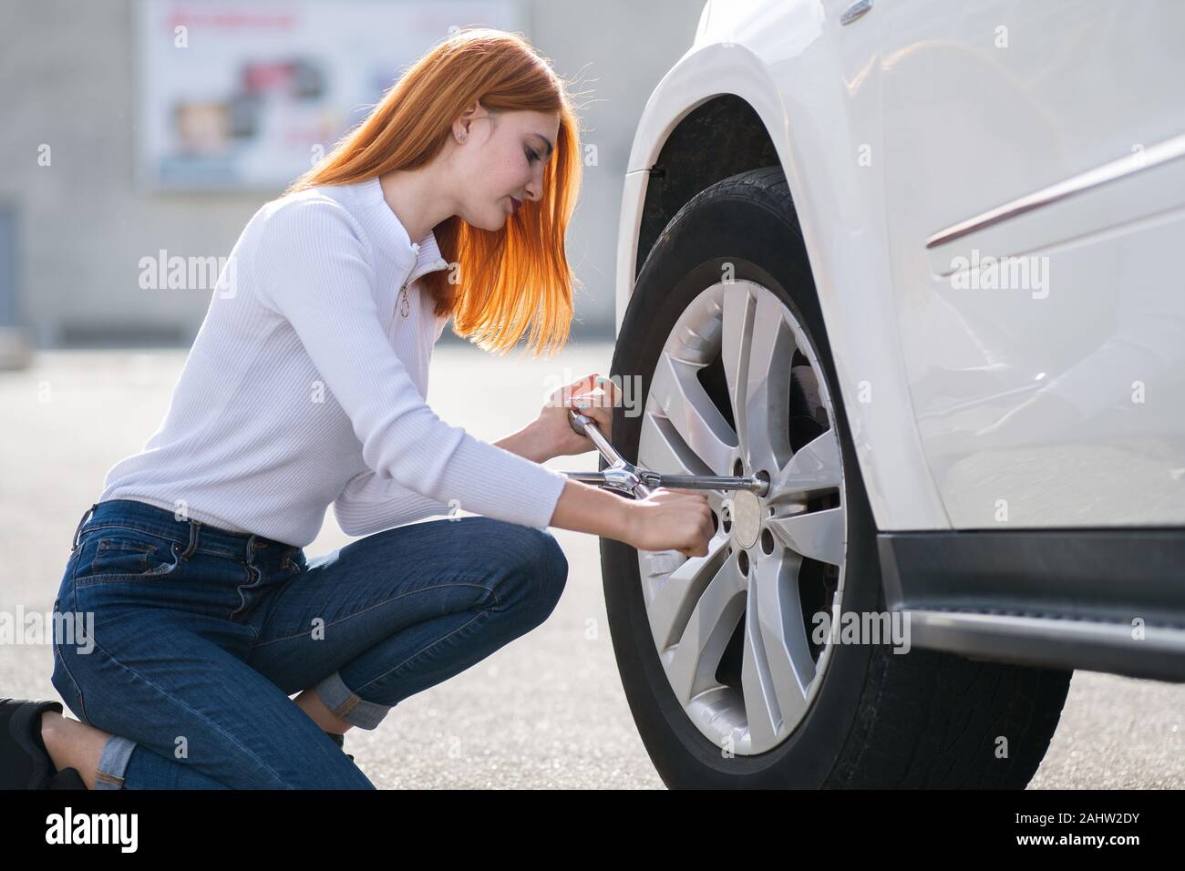 Mujer joven con la llave para cambio de ruedas en un coche roto