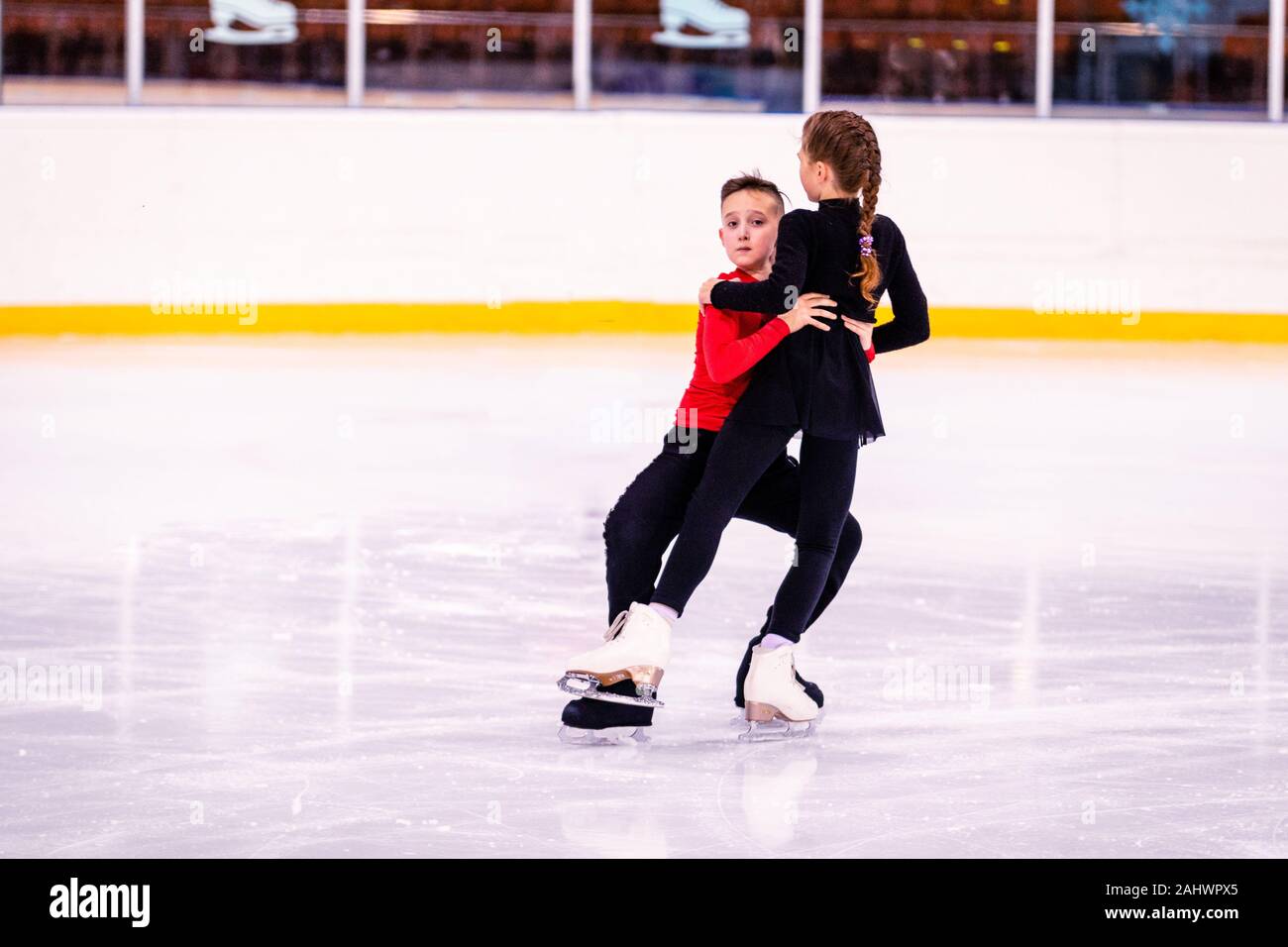 Formación de patinaje sobre hielo. Los niños atletas aprender par de  patinaje en el hielo. el niño realiza el apoyo de la chica, él está muy  centrado y diligente Fotografía de stock -