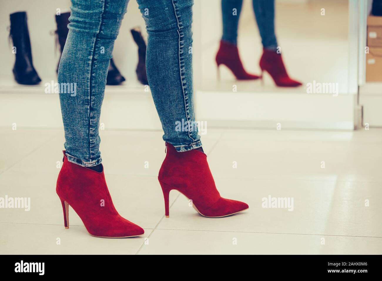 Mujer tratando en un nuevo par de zapatos con tacones altos mientras se  mira a sí mismo en el espejo, en una tienda de moda Fotografía de stock -  Alamy