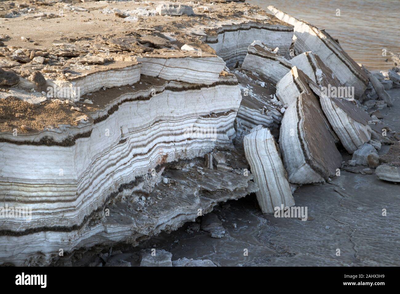 Capas anuales de sal y minerales depositados en la orilla del Mar Muerto, expuestos por la caída de los niveles de agua. Foto de stock