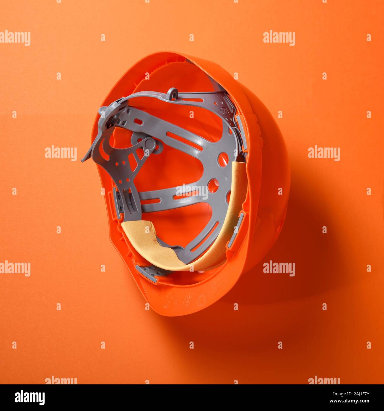 Un casco de seguridad hard hat naranja sobre un fondo naranja Foto de stock