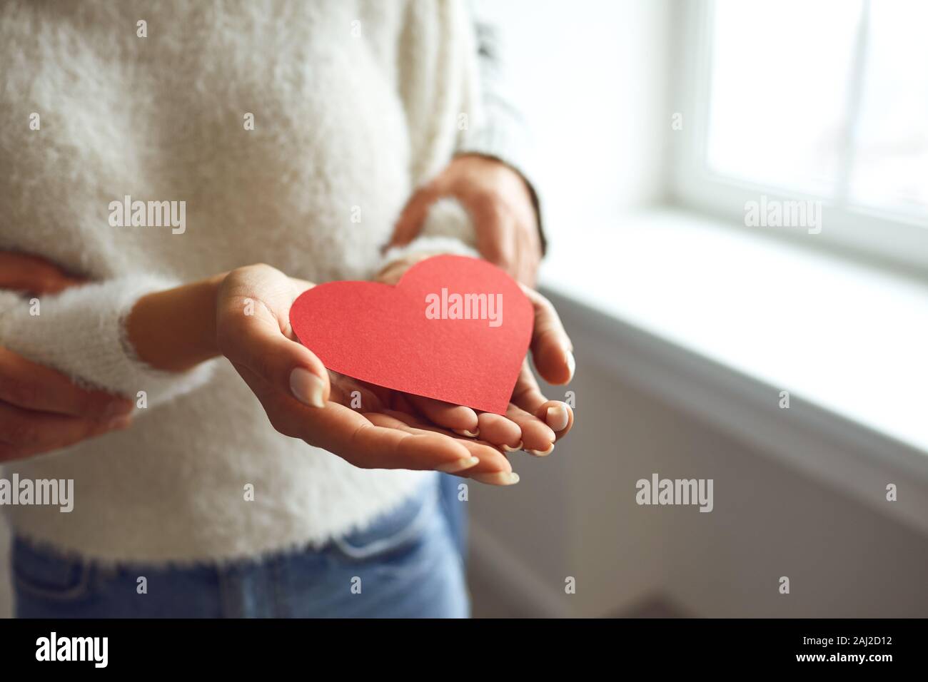 Corazón rojo en las manos de una pareja en el amor. El Día de San Valentín Foto de stock