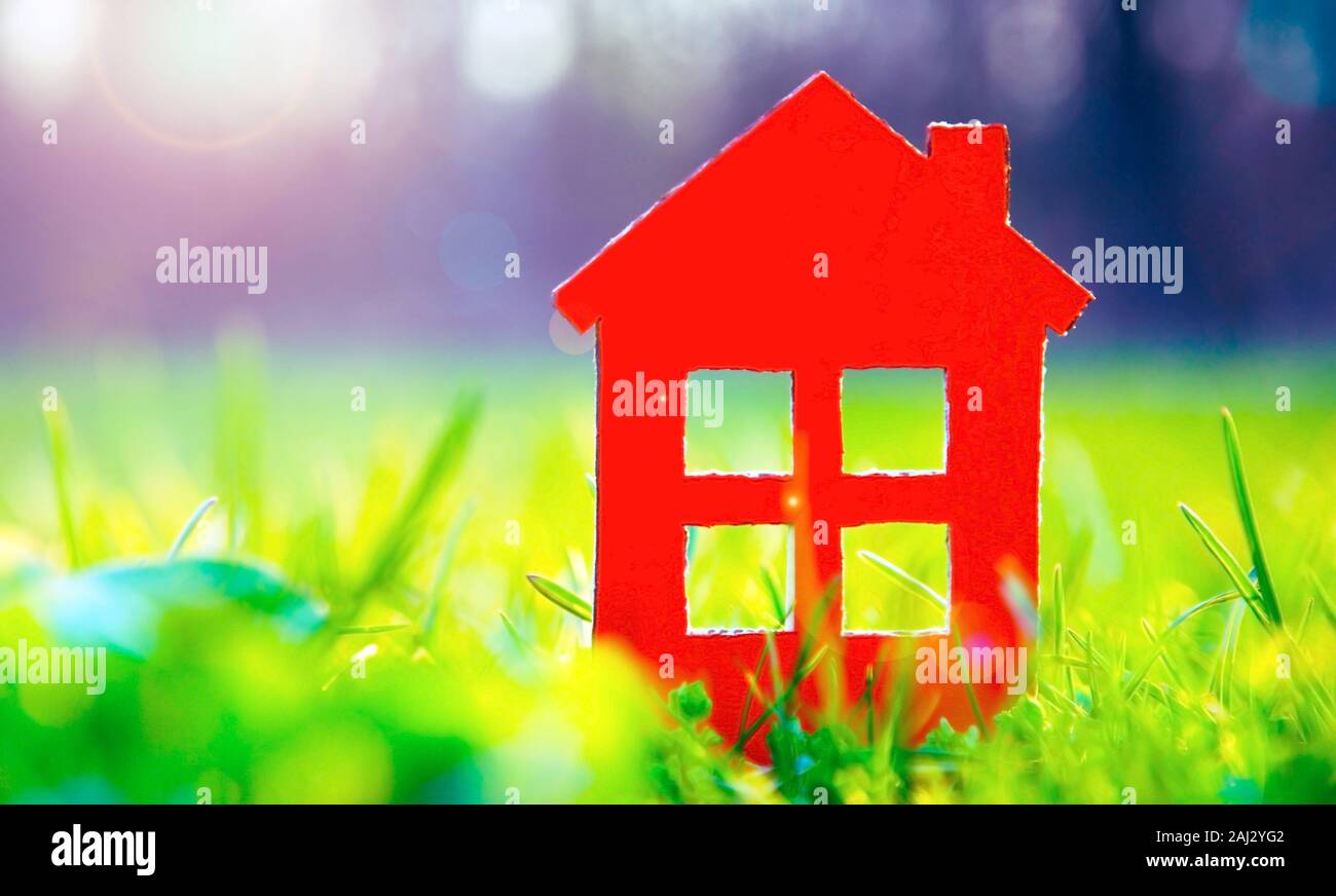 Silueta de la pequeña casa roja en hierba verde brillante bajo la luz del sol Foto de stock