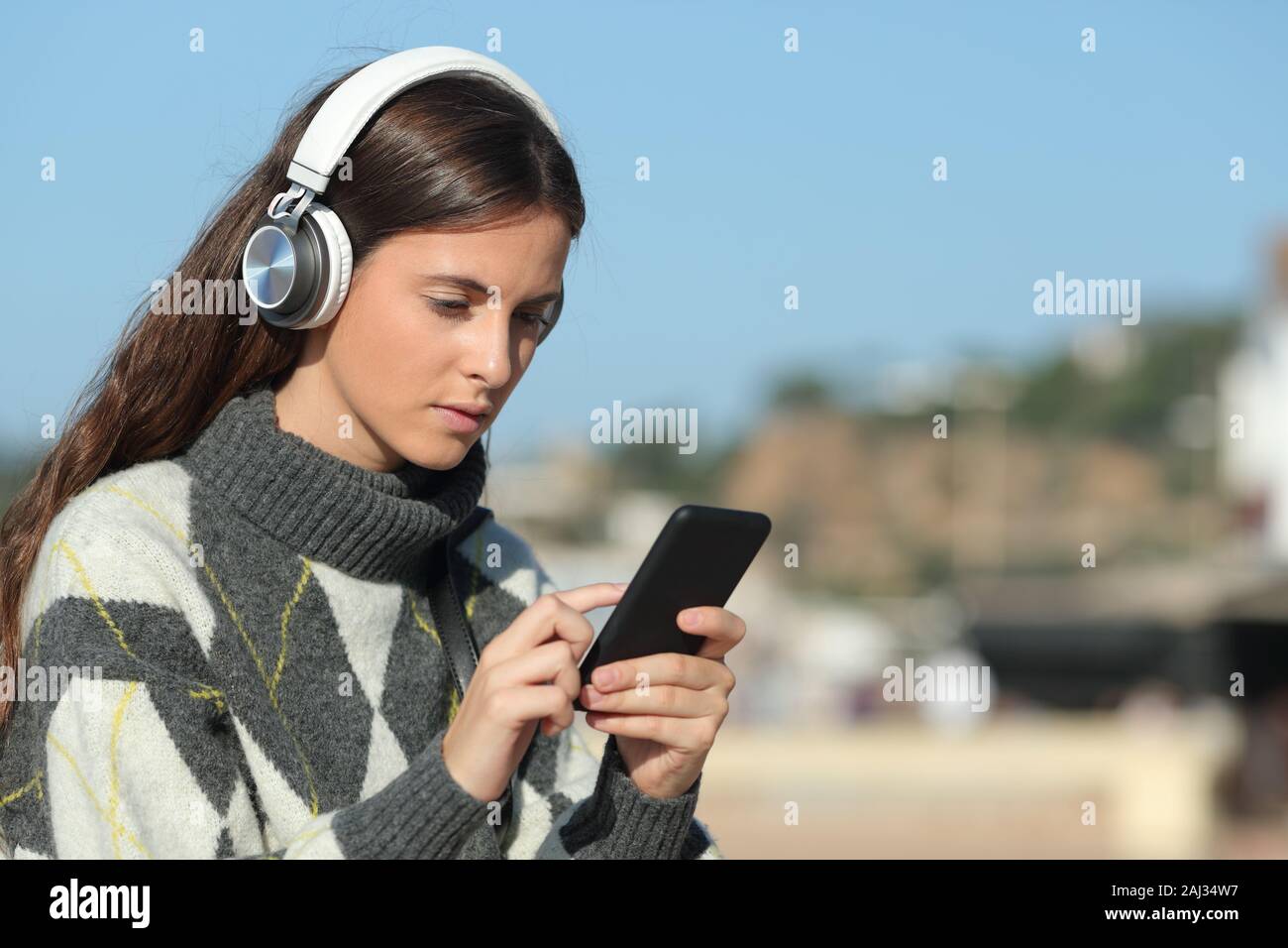 Chica seria usando audífonos para escuchar música en el teléfono móvil en  una ciudad Fotografía de stock - Alamy