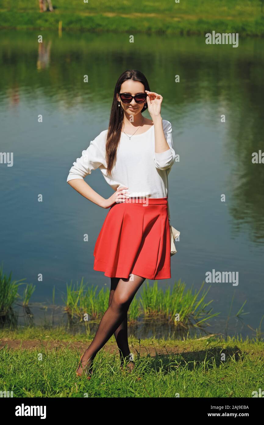 Retrato de una chica en falda roja y blusa blanca de pie en río Fotografía  de stock - Alamy
