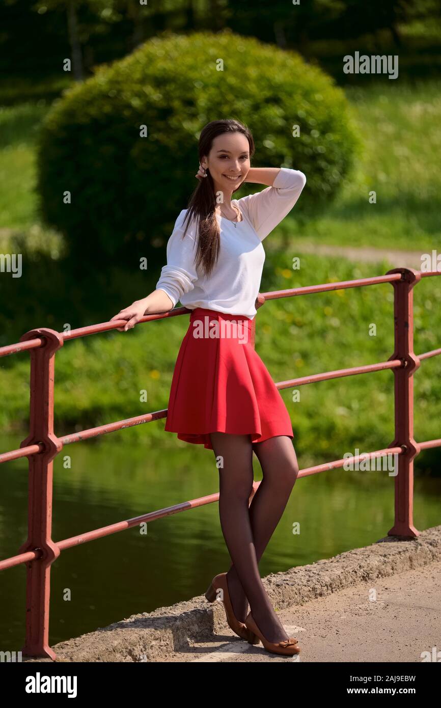 Retrato de una chica en falda roja y blusa blanca, apoyada contra una  baranda de puente en la ribera del río Fotografía de stock - Alamy