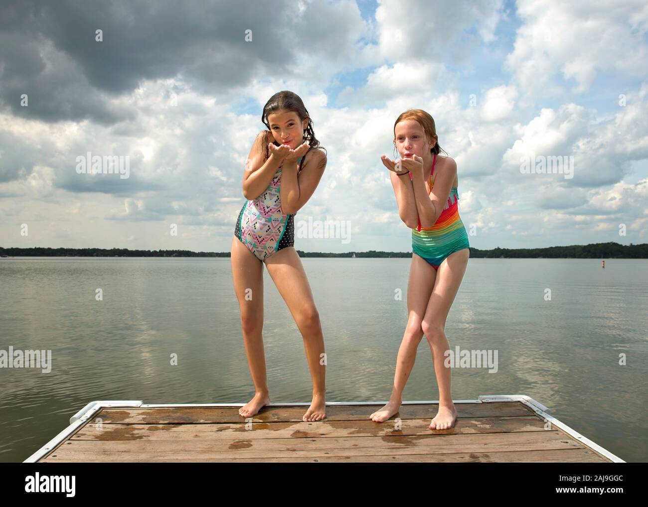 Dos niñas en trajes de baño soplan los besos final de Dock by Lake Fotografía de stock - Alamy