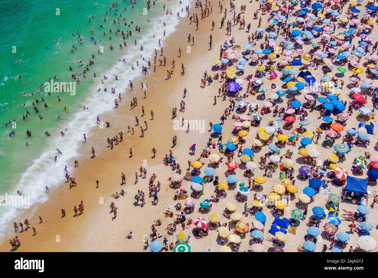 Río de Janeiro, Brasil, vista aérea de la playa de Copacabana mostrando coloridas sombrillas y gente bañarse en el mar en un día de verano. Foto de stock