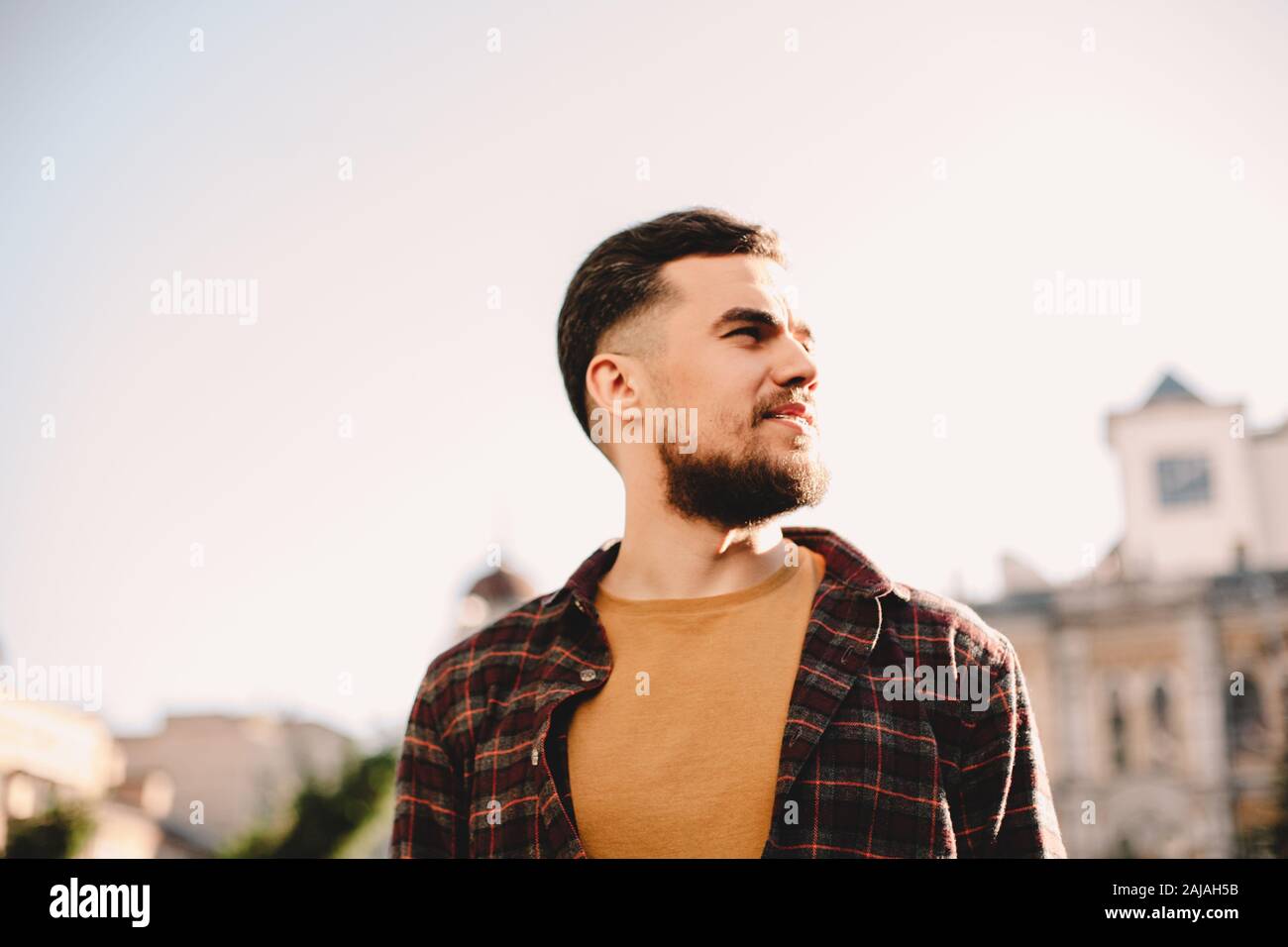 Retrato de un hombre joven y confiado en hipster contra el cielo despejado en la ciudad Foto de stock