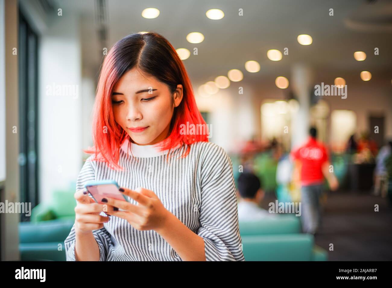 Retrato de una joven mujer de pelo rojo casual mirando teléfono móvil - Estudiante chica prestando atención al calendario en el smartphone Foto de stock