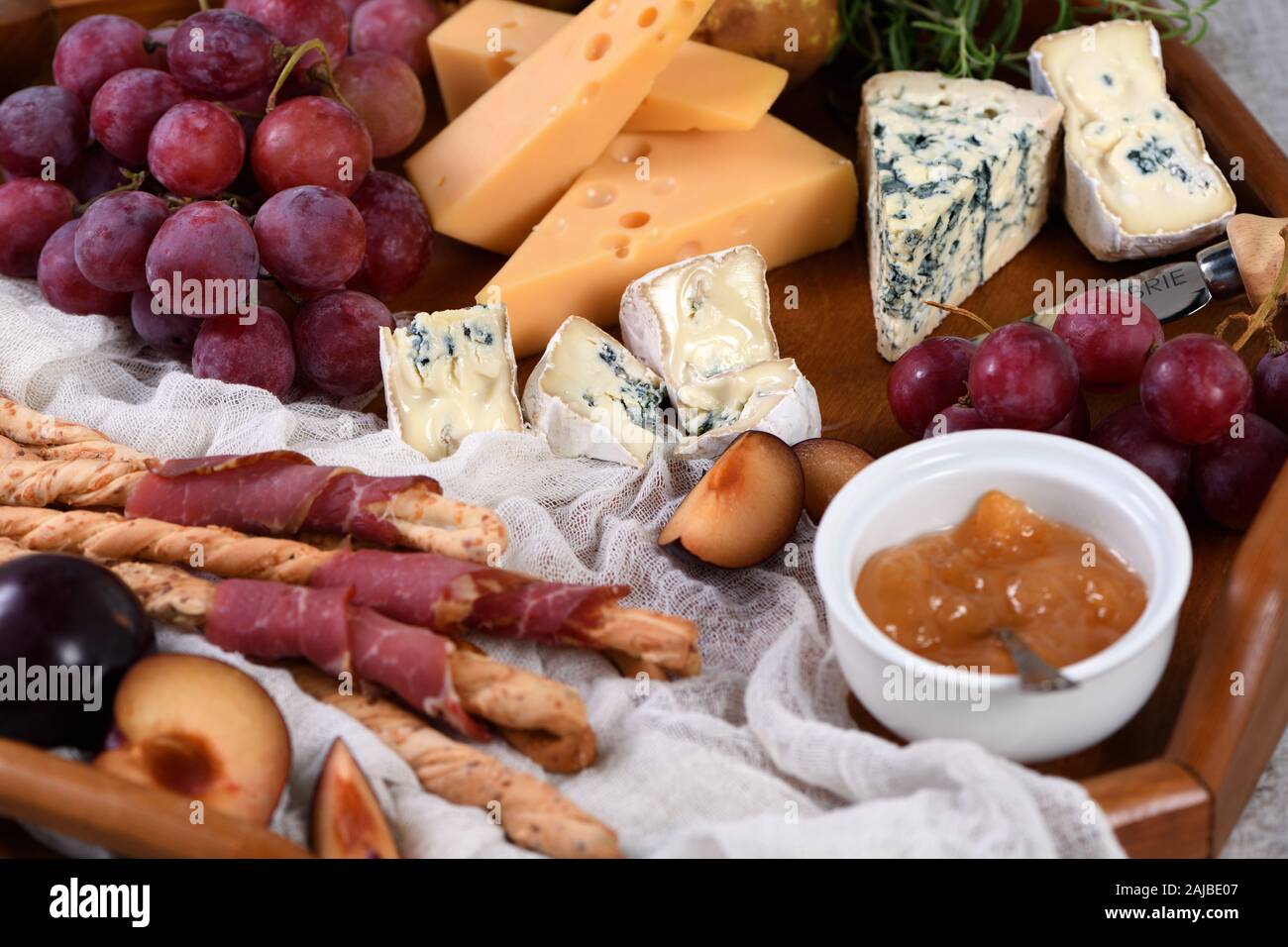 El antipasto. Plato con crujientes grissini envuelto en tocino secados al sol, rebanadas de queso brie, camembert, queso azul, y radamer vid de uva moscatel con FRU Foto de stock