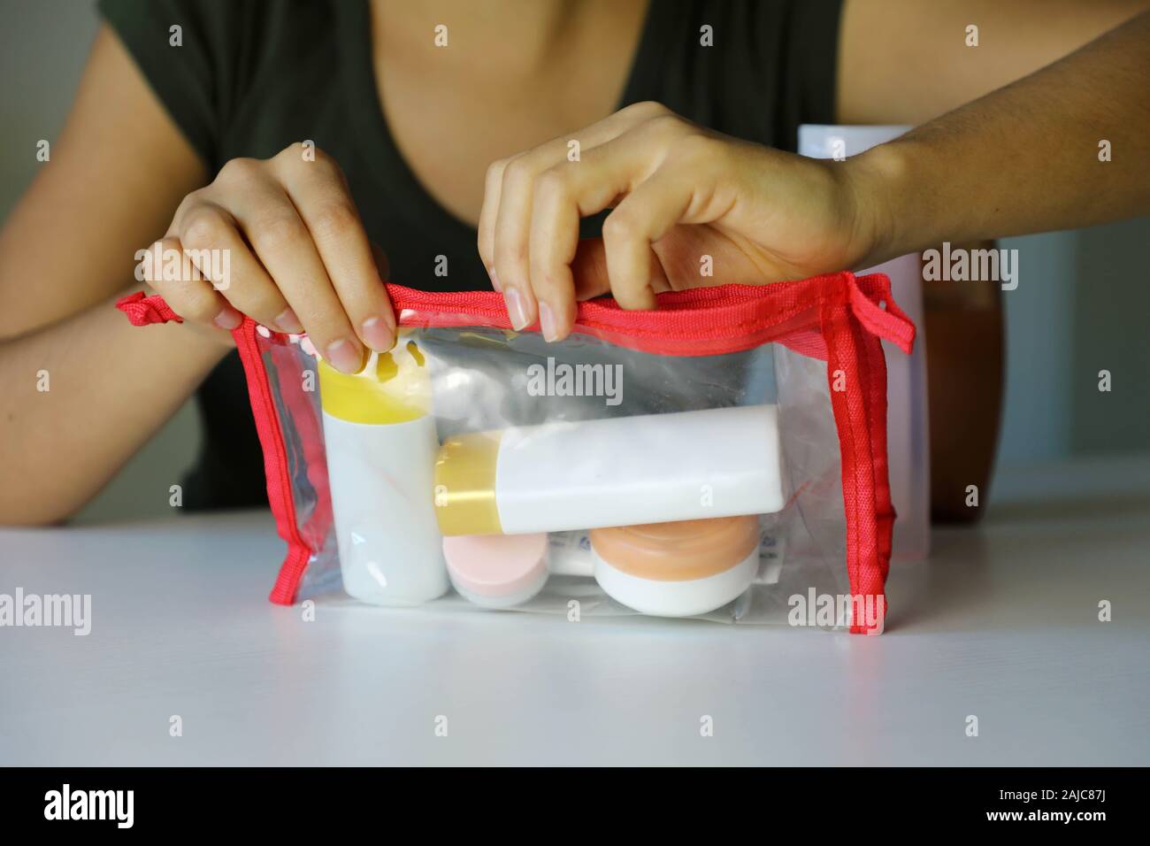 Mujer Cierre la bolsa transparente con kit de viaje para transportar  productos cosméticos en avión Fotografía de stock - Alamy