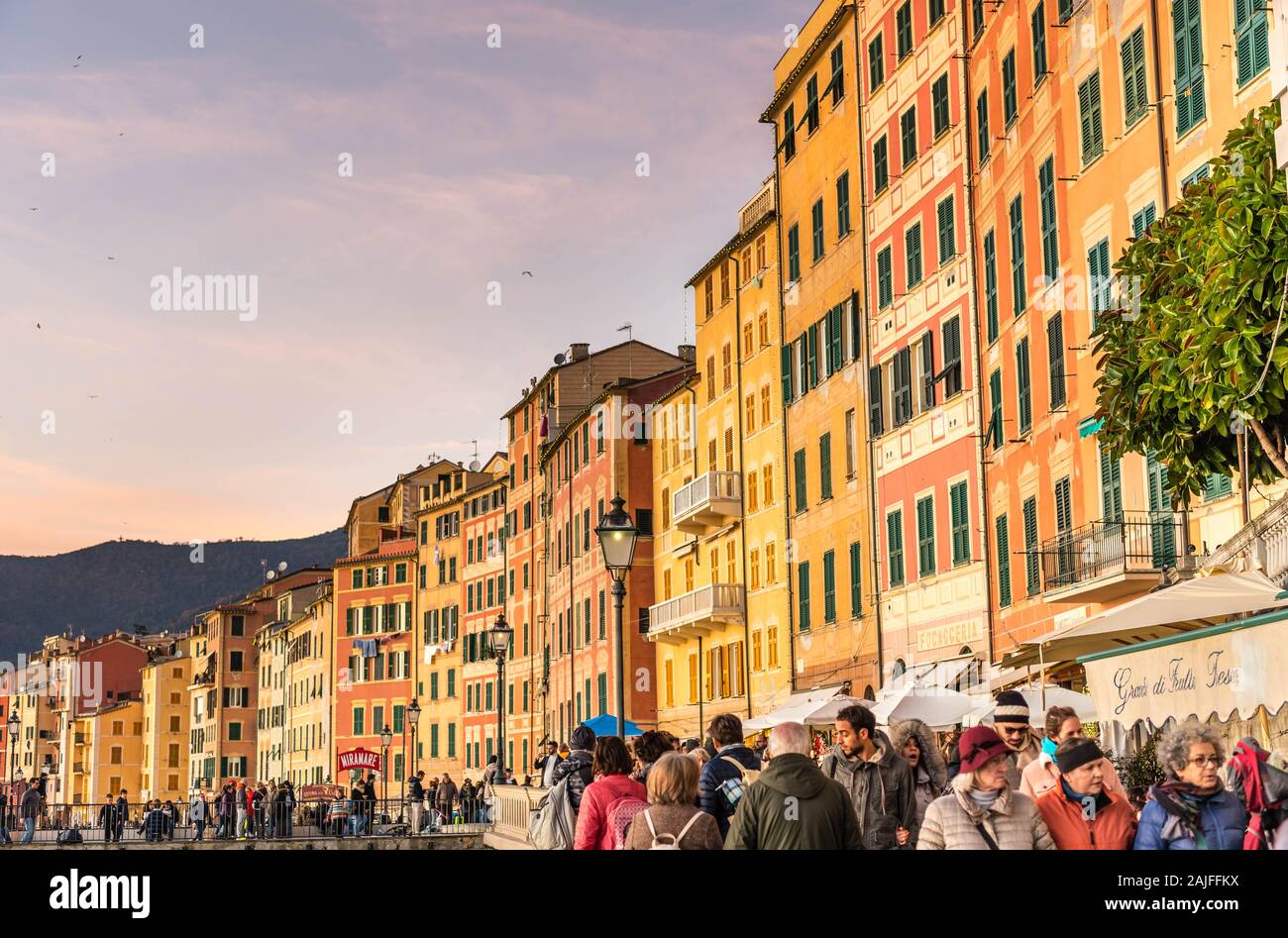 Camogli, Génova, Italia: Hermosa vista al atardecer de la aldea costera italiana, casas tradicionales de Liguria con fachadas multicolores, gente paseando Foto de stock