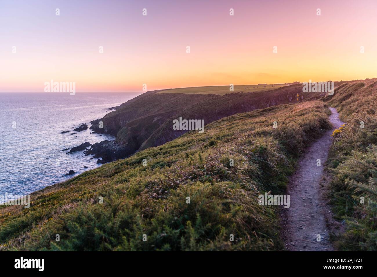 Panorama vista del atardecer de Ballycotton Cliff Walk, Condado de Cork, Irlanda, al atardecer, mar tranquilo atardecer horizonte, camino solitario, popular sendero Foto de stock