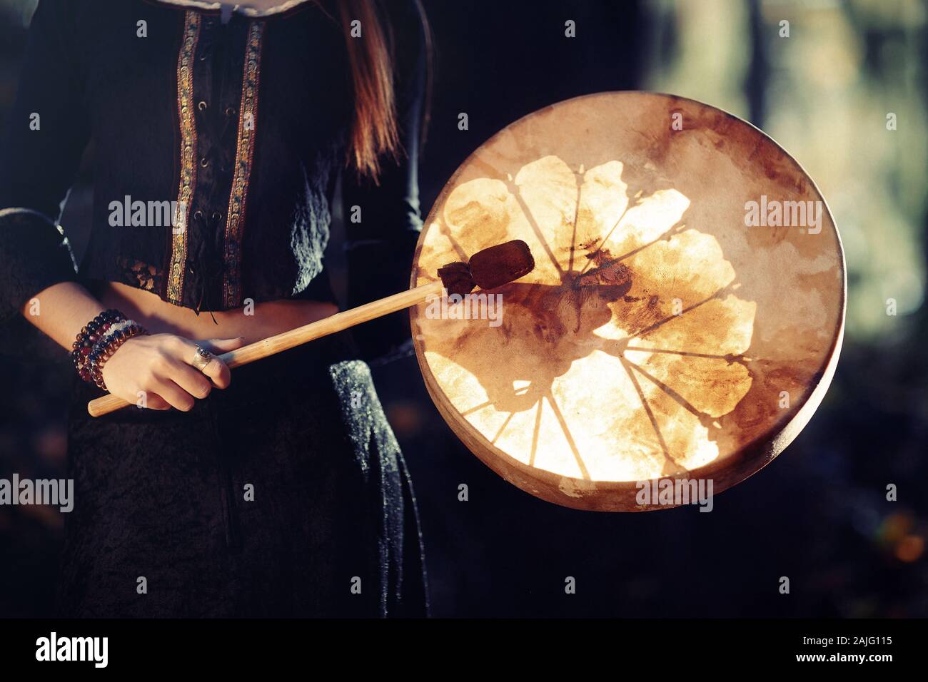 Hermosa niña jugando chamánicas chamán en tambor de bastidor en la naturaleza. Foto de stock