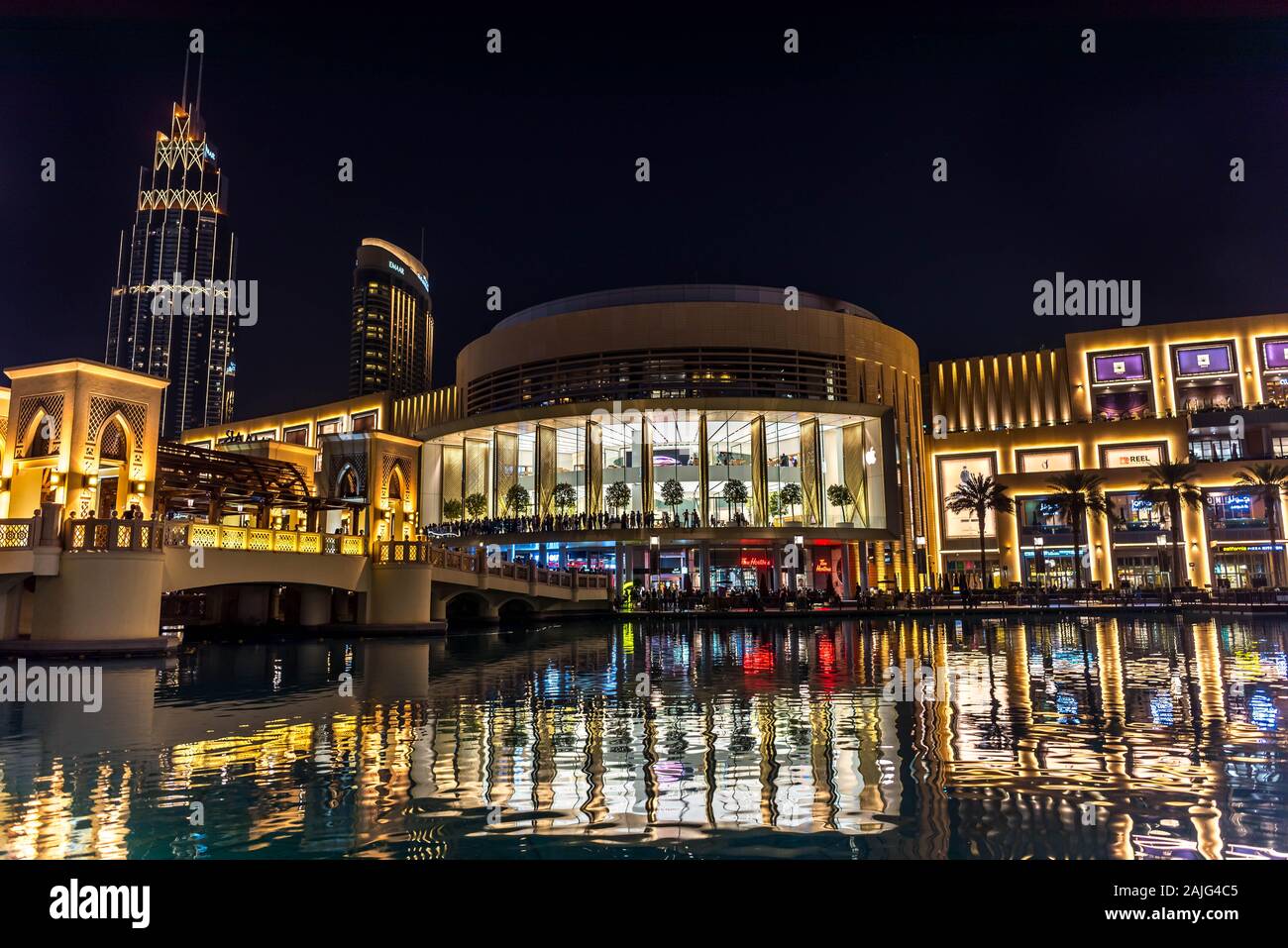Dubai, Emiratos Árabes Unidos: Exterior de Dubai Mall por la noche enfrente de la torre Burj, escaparates iluminados, con marcas de moda de lujo Foto de stock