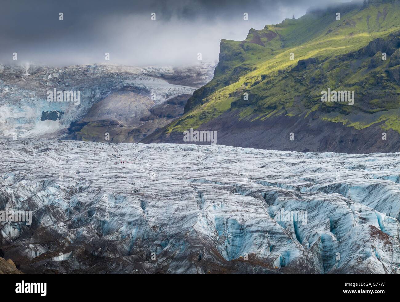Islandia en verano: impresionante paisaje islandés con hielo azul glaciar con grietas, montañas cubiertas de hierba verde y cielo espectacular Foto de stock