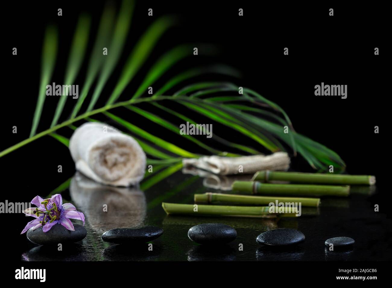 Hermoso balneario composición con passiflora, bambú y piedras sobre fondo negro Foto de stock