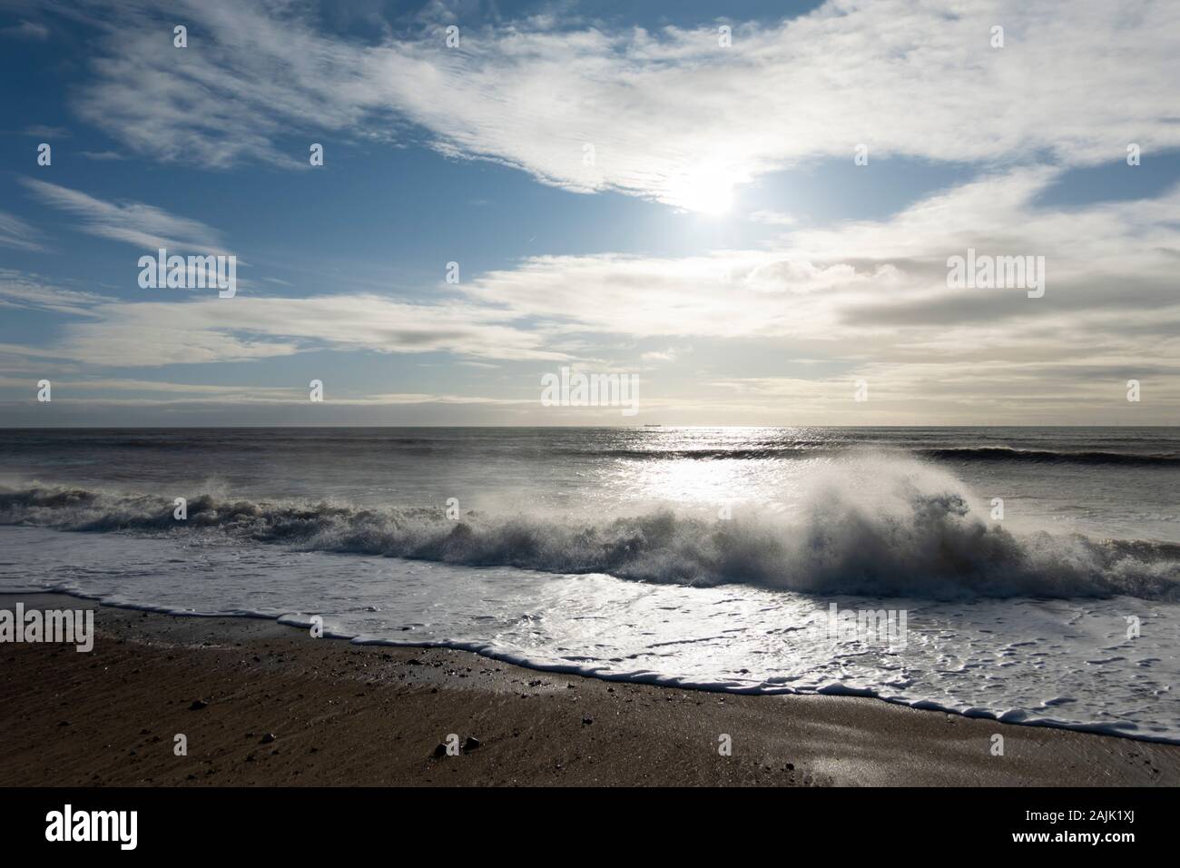 Ola rompiendo en Pebble Beach retroiluminada por el sol, el Shoreham por mar; en West Sussex, Inglaterra, Reino Unido, Europa Foto de stock