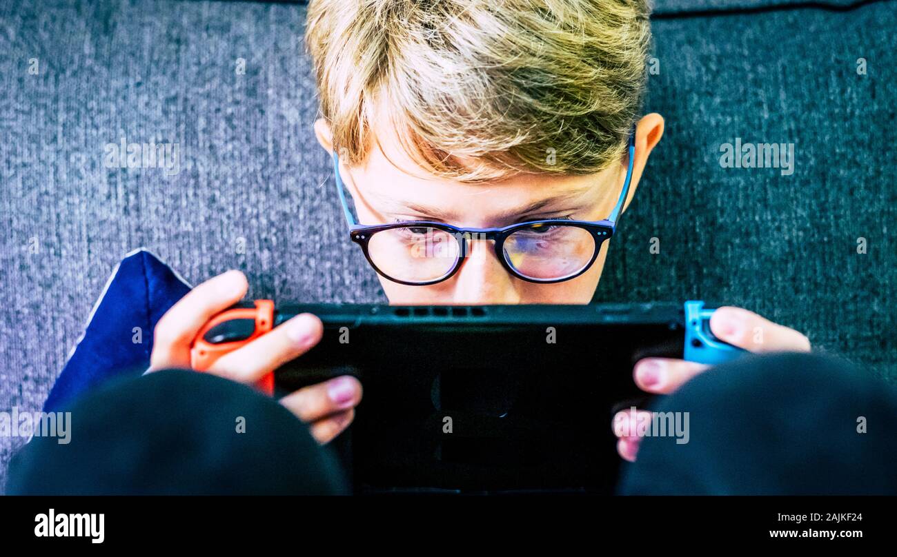 Jóvenes y niños caucásicos concentrado con el dispositivo portátil jugador jugando con tecnología juegos Internet conectado con amigos - video juego adicción Foto de stock