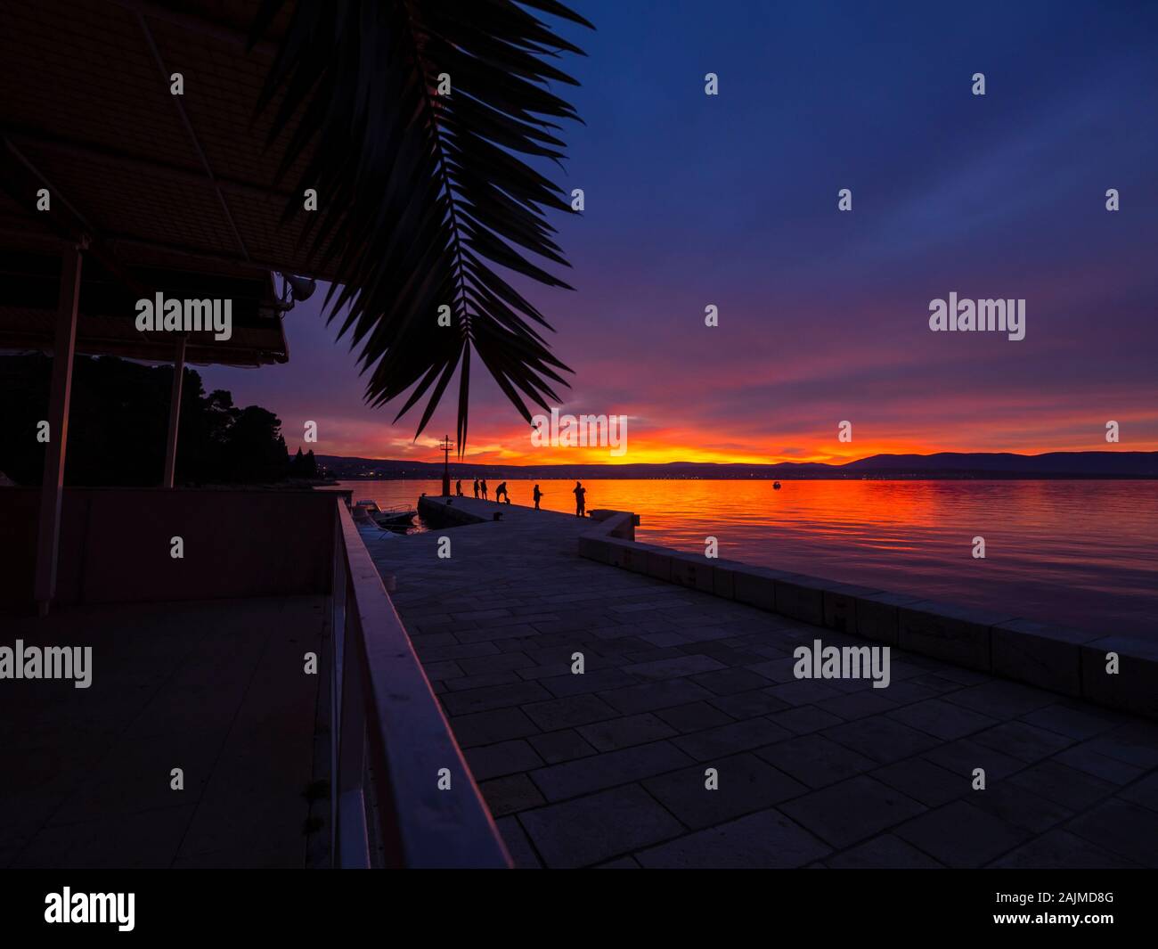Los pescadores en seawall antes del atardecer paisaje de pequeño puerto en Malinska en Croacia Foto de stock
