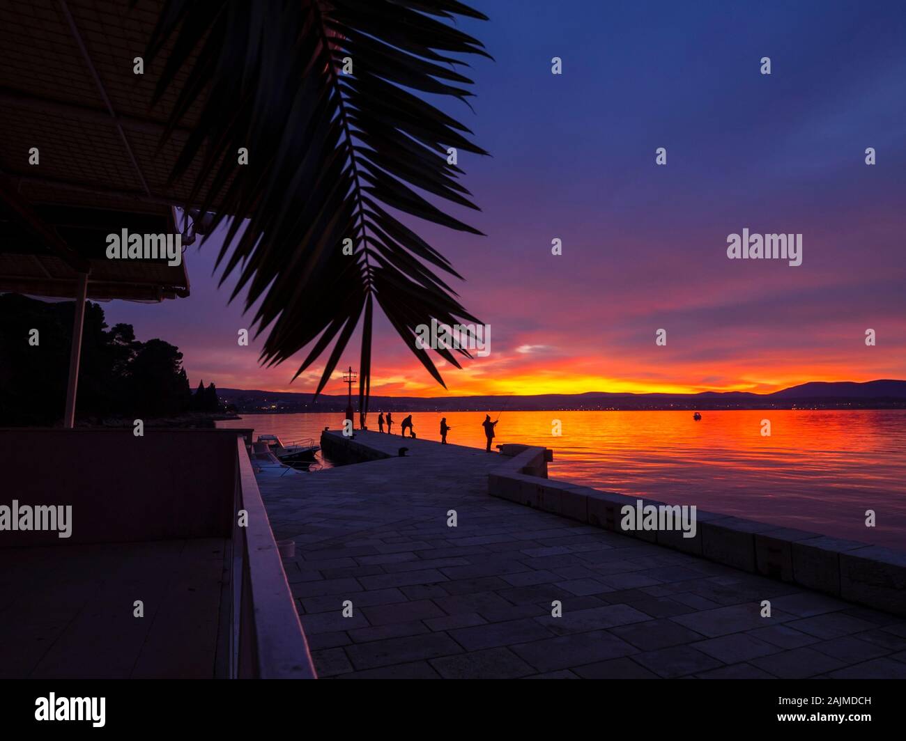 Los pescadores vista desde la parte trasera espejo atrás en seawall permanente antes del atardecer paisaje de pequeño puerto en Malinska en Croacia natureaddicted natureaddict Foto de stock