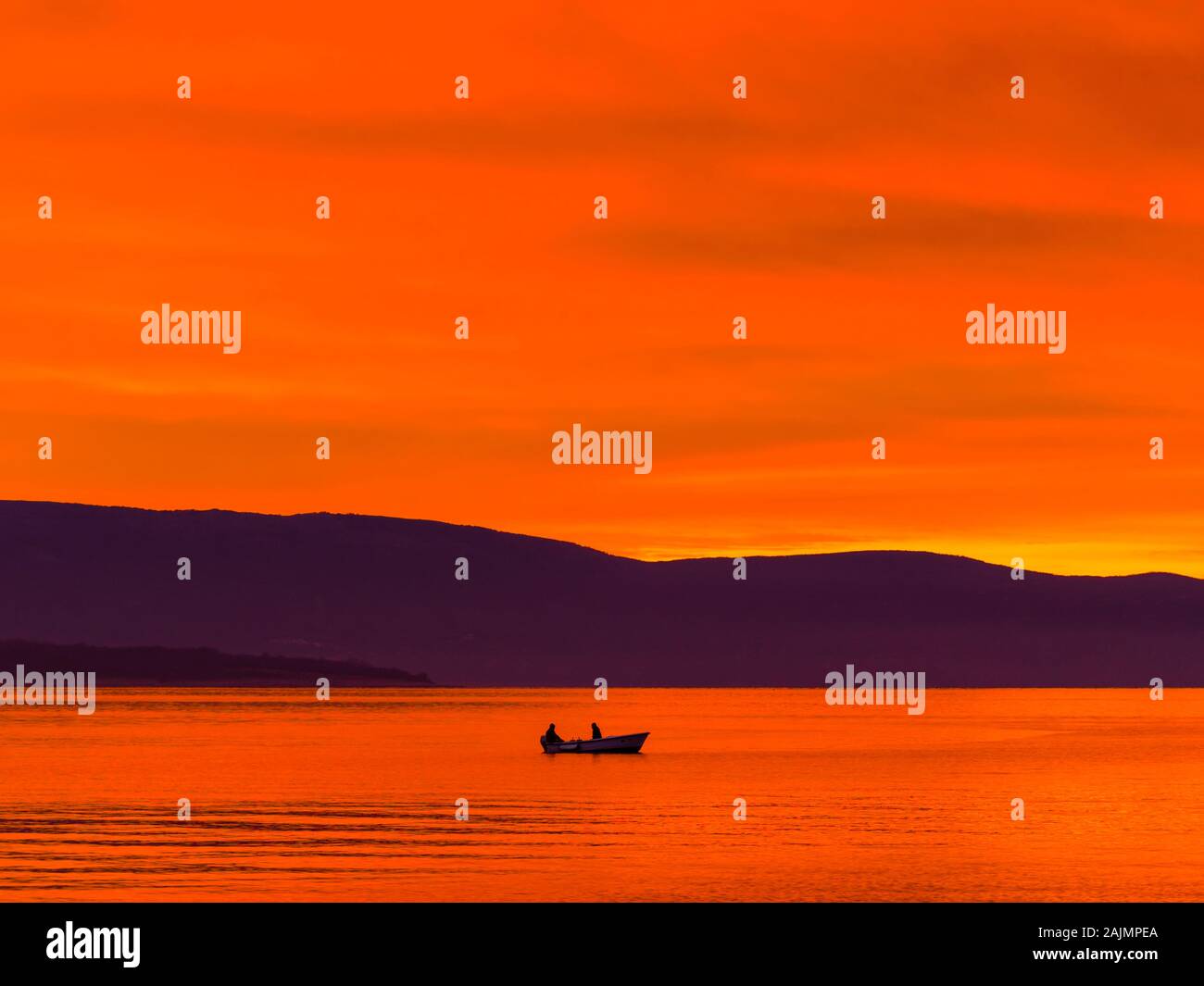 Barco solitario con dos pescadores antes de la gloriosa puesta de sol del mar paisaje panorama Foto de stock