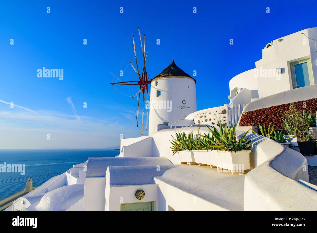 El molino de viento y edificios blancos tradicionales hacia el mar Egeo en Oia, Santorini, Grecia Foto de stock