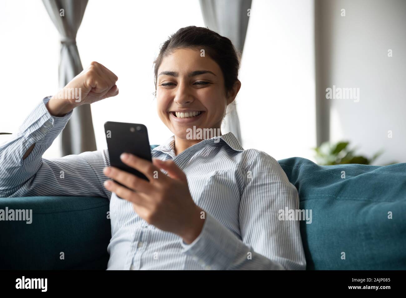 Emocionada alegría chica india teléfono espera celebrar app ganadora de la puja Foto de stock