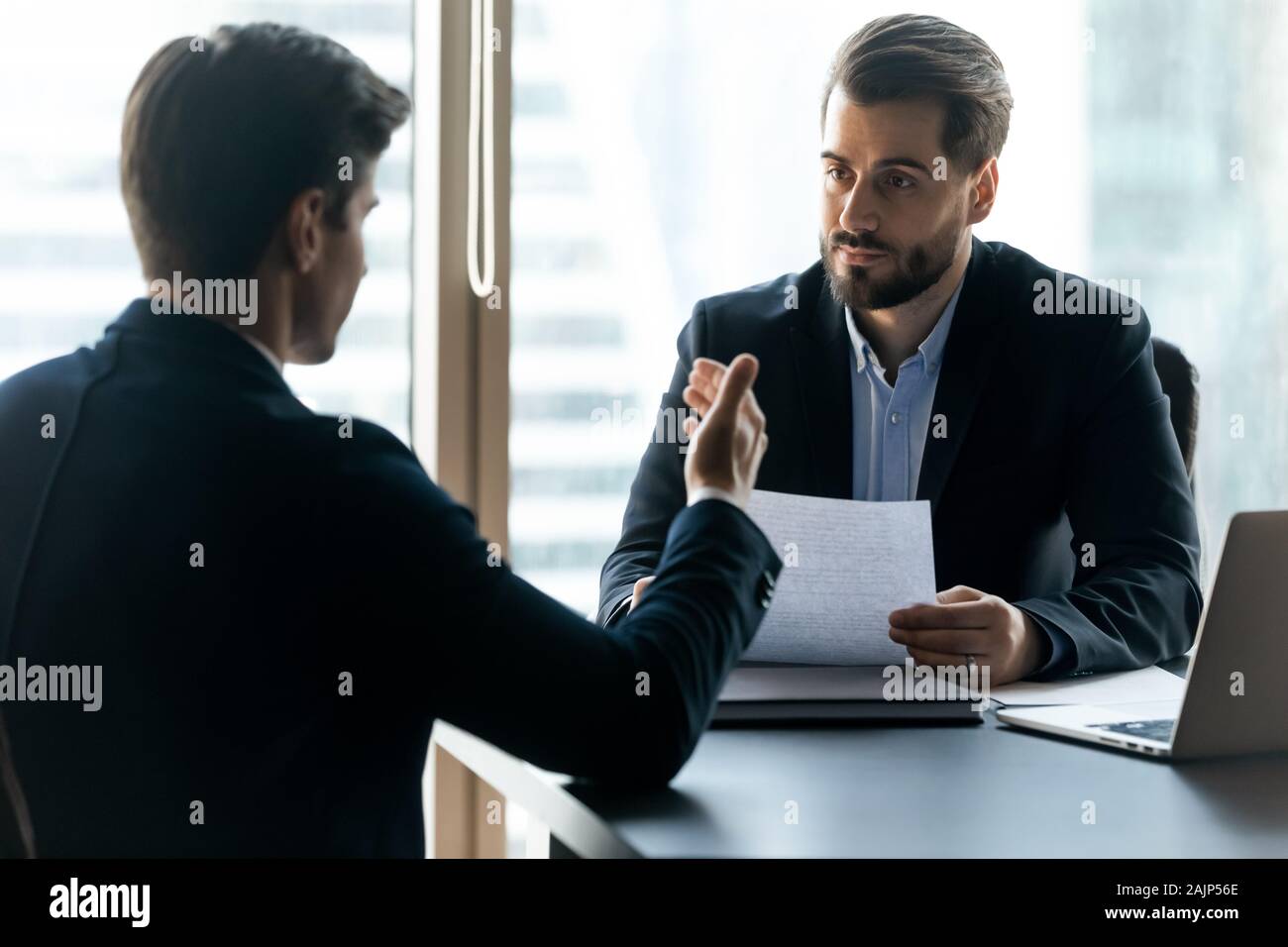 Hable con candidatos varones caucásicos empleador en oficina de la entrevista Foto de stock