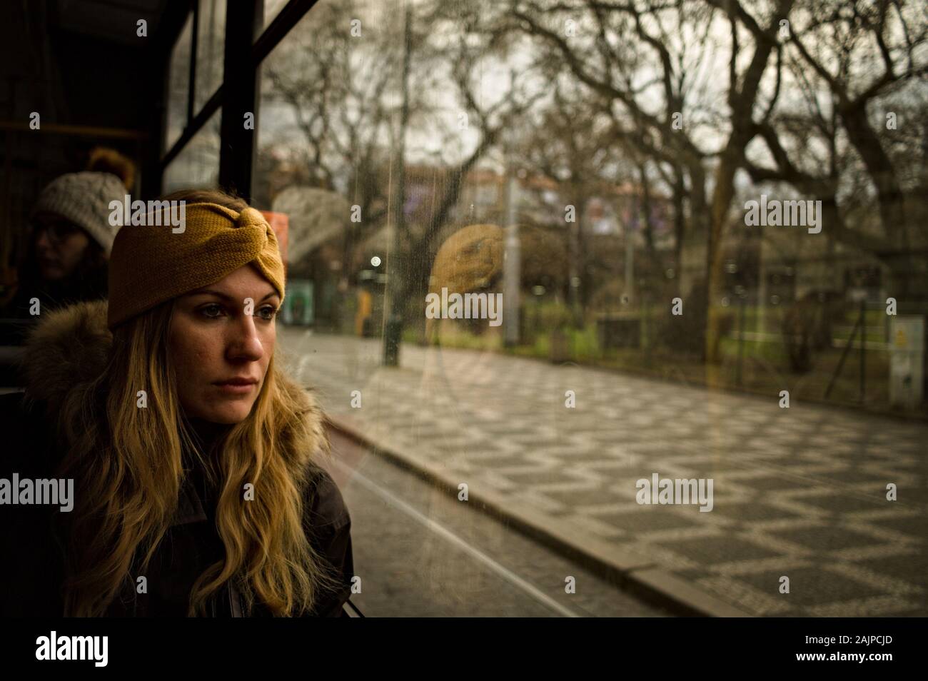 Praga, República Checa - 30 de diciembre de 2019: una mujer rubia con una diadema amarilla está mirando afuera a través del cristal de un autobús Foto de stock