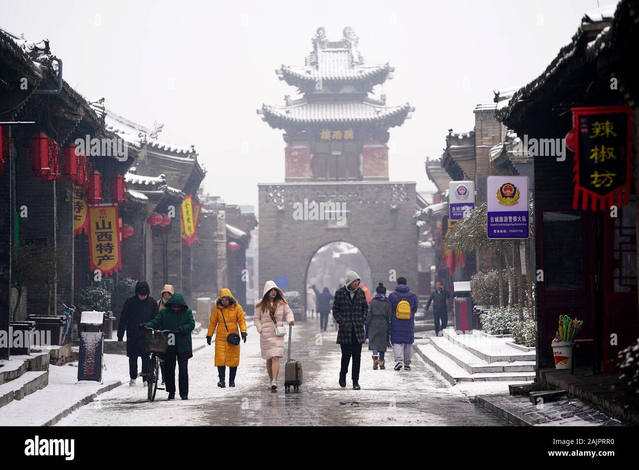 Pingyao, China. 5 de enero, 2020. Los turistas visitan el nevado Pingyao Antigua ciudad en el norte de la Provincia china de Shanxi, 5 de enero de 2020. Fundada en el siglo 14, la antigua ciudad de Pingyao es un ejemplo excepcionalmente bien conservado de una ciudad chinos tradicionales, que fue nombrada Patrimonio de la Humanidad por la UNESCO en 1997. Crédito: Zhan Yan/Xinhua/Alamy Live News Foto de stock