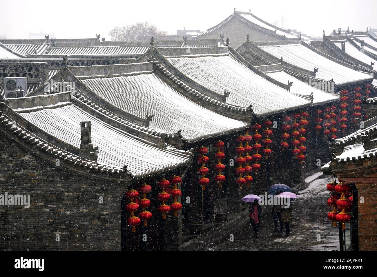 Pingyao, China. 5 de enero, 2020. Los turistas visitan nevados Pingyao Antigua ciudad en el norte de la Provincia china de Shanxi, 5 de enero de 2020. Fundada en el siglo 14, la antigua ciudad de Pingyao es un ejemplo excepcionalmente bien conservado de una ciudad chinos tradicionales, que fue nombrada Patrimonio de la Humanidad por la UNESCO en 1997. Crédito: Zhan Yan/Xinhua/Alamy Live News Foto de stock